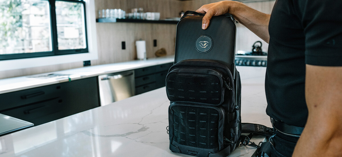 Man in kitchen putting Vaultek safe into bag