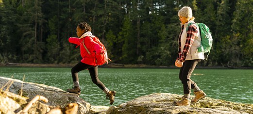 mom & child crossing rocks near river